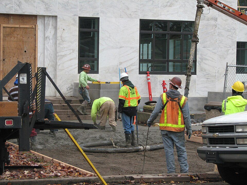 Concrete crew finishing a fresh pour in safety gear